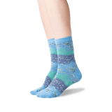 A pair of crew socks with a horizontal striped pattern in shades of blue, teal, and purple, featuring a fish design, shown on a model's feet against a white background. thumbnail