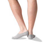 A close-up of a person's lower legs and feet wearing light gray low-cut no-show socks against a plain white background. thumbnail