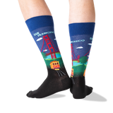 A pair of crew socks worn on feet, featuring a colorful San Francisco-themed graphic with the Golden Gate Bridge, trolleybus, and 'SAN FRANCISCO' text on a white background. thumbnail