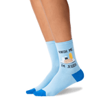 Light blue crew socks with blue toes, heels, and soles, featuring a graphic of a Passover Seder plate with the text 'KNISH ME, I'M JEWISH' worn on a model's feet against a white background.