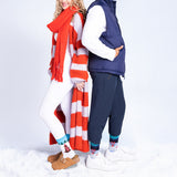 Two people standing in the snow wearing winter clothing with a red scarf and blue vest. thumbnail