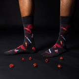 Black socks with red dragons, potions, and sword designs worn by a person on a black background thumbnail