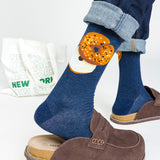 Person wearing blue socks with a bagel design, paired with brown shoes and a white bag with 'New York' text. thumbnail