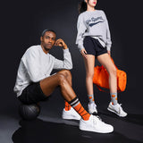 Two people wearing gray sweatshirts with 'Go Sports' text, black shorts, and orange socks on a dark background. thumbnail
