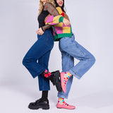 Two people hugging, one wearing a colorful sweater and jeans, the other in black top and blue jeans, on a white background. thumbnail
