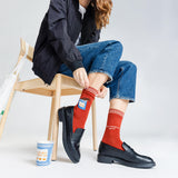 Person wearing red socks with text design, sitting on a chair with a white background