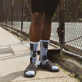 Person wearing black and white striped socks with sandals on a sidewalk.