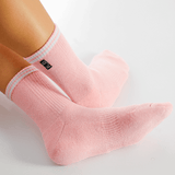 Pink socks with white stripes worn by a person on a light gray background thumbnail