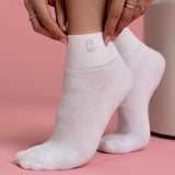 White socks with a small embroidered popsicle on a pink background