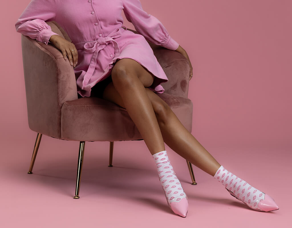 Person wearing a pink dress and matching shoes with white polka dots on a pink background
