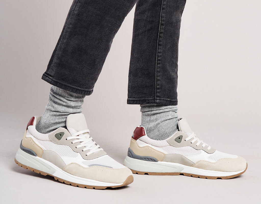 Man wearing faded gray denim jeans, trendy sneakers, and light gray crew socks.