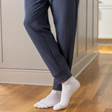 Person wearing navy pants and white socks on a wooden floor. thumbnail