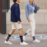 Two people walking on a sidewalk wearing denim jackets and white pants. thumbnail
