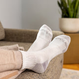Person wearing white socks with text, sitting on a couch in a home setting.