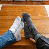 Two pairs of socks, one gray and one white, on a wooden floor. thumbnail