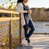 Woman standing on a bridge holding a coffee cup with a scenic background