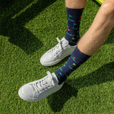 White sneakers with colorful golf-patterned socks on a grassy surface