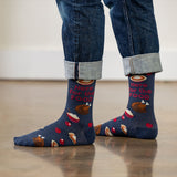 Person wearing blue socks with Thanksgiving-themed design and rolled-up jeans on a light wooden floor. thumbnail