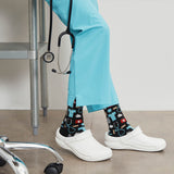 Person wearing light blue scrubs with patterned socks and white shoes, standing in a medical setting.