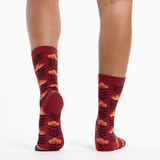 Red socks with floral pattern worn by a person on a white background