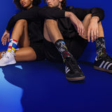 Two people sitting on a blue floor wearing colorful art-themed socks.