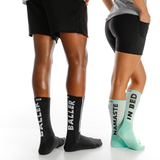Two pairs of socks with text on them worn by people, one black with 'BALLER' and one green with 'NAMASTE IN BED'.