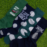 Four pairs of socks with humorous golf-themed designs on a grass background