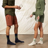 Two people wearing socks with recycling symbols, one in navy and the other in white, against a neutral background. thumbnail