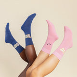 Two pairs of socks, one blue and one pink, on feet against a beige background.