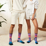 Two people wearing matching white outfits with colorful socks in a casual setting.