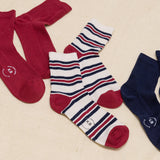 Set of red, white, and blue striped socks with a brand logo on a beige background