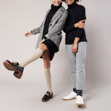 Two people posing together wearing stylish outfits with a plain background thumbnail