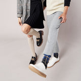 Two people wearing different styles of socks with a neutral background