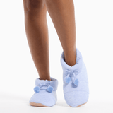 Light blue slippers with pom-poms worn by a person on a white background thumbnail