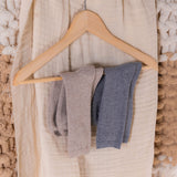 Three pairs of socks on a wooden hanger against a textured beige background thumbnail