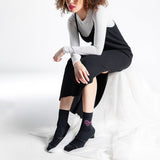 Woman wearing black socks with a pink rhinestone bow on a white background. thumbnail