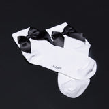 White socks with black bows on a black background, featuring the brand 'k.bell'.