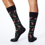 Back view of HOTSOX men's black crew socks on model with a repeat football pattern.
